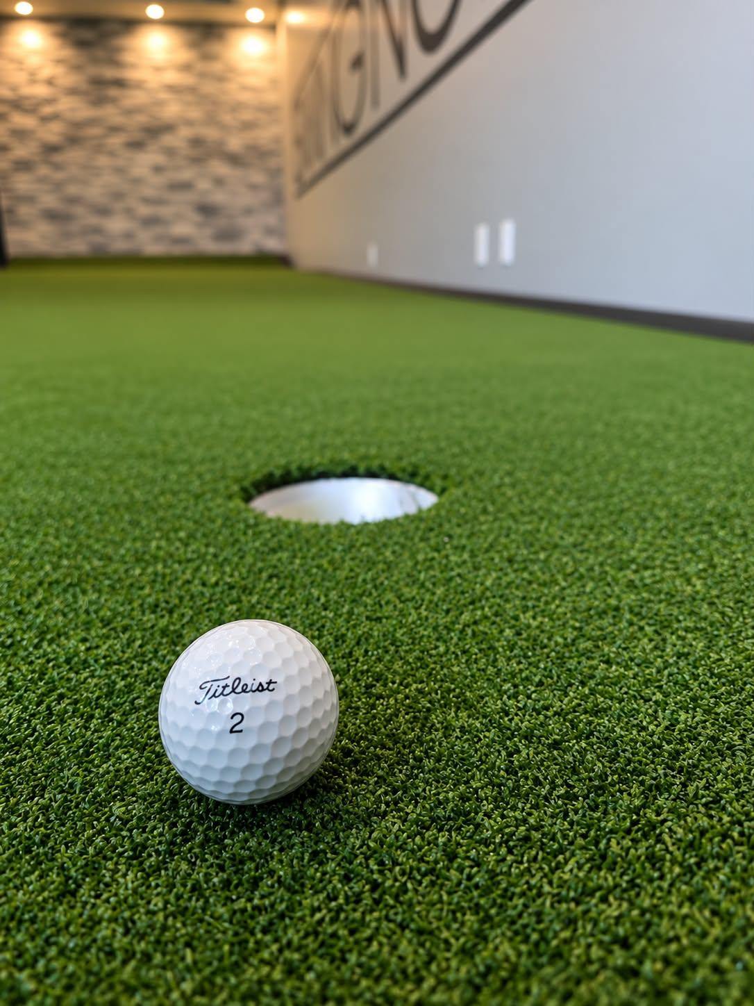 Swinging Iron logo, a golf performance centre interior with putting green and golf simulator SE Calgary Alberta
